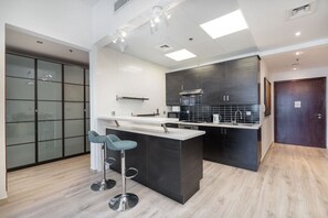 A modern kitchen with a central island, bar stools, and dark cabinetry.