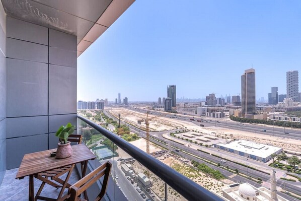 A balcony with a view of a cityscape, including high-rise buildings and a highway.