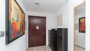 A hallway with a wooden door, black storage units, and abstract paintings on the walls.