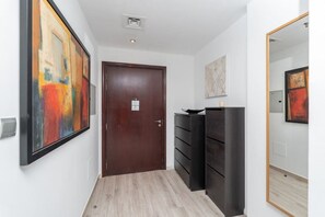 Un pasillo con una puerta de madera, almacenaje negro y cuadros abstractos en las paredes.