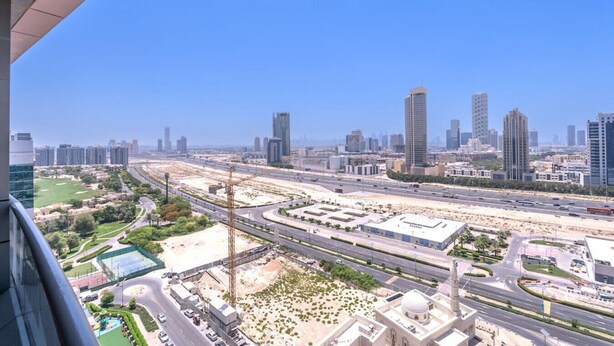 A cityscape with modern high-rise buildings, a highway, and a mosque with a dome.