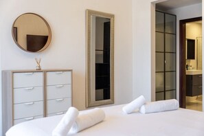 Et hotelværelse med seng, garderobeskab, spejl og skab.