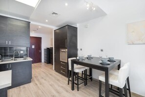 A modern kitchen with dark cabinetry, a built-in oven, and a dining area with a table set for four.