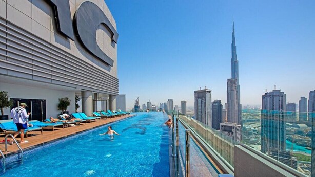 Una piscina en la azotea con vistas al horizonte urbano, incluyendo un rascacielos destacado.