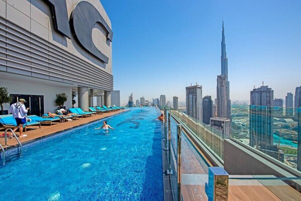 A rooftop pool with a city skyline view, including a prominent skyscraper.