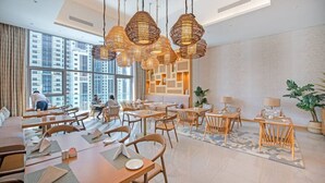 Un moderno vestíbulo de hotel con techos altos, amplias ventanas y una variedad de zonas de estar.