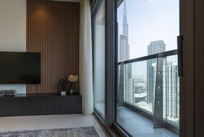 A modern living room with a large window, a flat-screen TV, and a view of the city skyline.