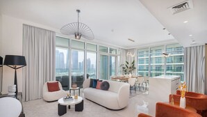 Un salón amplio con un sofá moderno, zona de comedor y grandes ventanas con vistas a la ciudad.