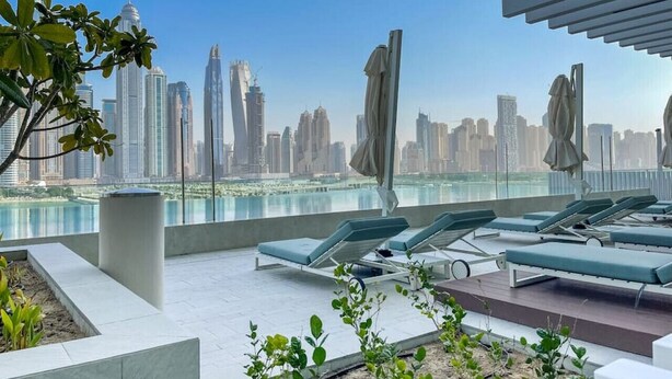 Terraza en la azotea con sillones y sombrillas, con vista a un horizonte urbano.