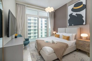 Quarto de hotel moderno com uma cama grande, televisão de tela plana, escrivaninha e janela com vista para a cidade.