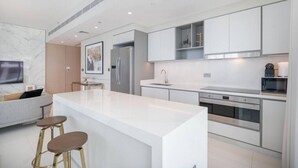 Une cuisine moderne dotée d’un îlot central, d’appareils électroménagers en acier inoxydable et d’un design minimaliste.