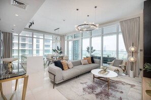 Ein geräumiges Wohnzimmer mit einer großen Couch, einem Couchtisch und einem Essbereich mit einem Glastisch und Stühlen.
