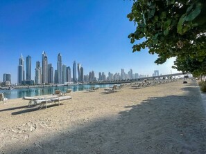 Ein Strand mit Liegestühlen und Blick auf eine Stadtlandschaft.
