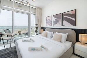 Habitación de hotel con una cama grande, un escritorio, una silla y un balcón con vistas.