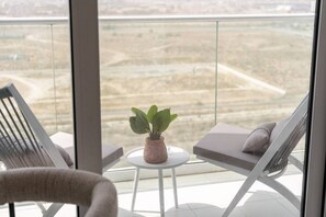 Un balcon avec deux fauteuils blancs, une petite table blanche et un pot de fleurs.