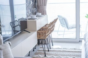 A modern kitchen with a dining area, large windows, and a view of the outdoors. - Floral Charm studio in Damac Hills by Suiteable (Dubai)