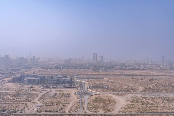 An aerial view of a city with a prominent highway, buildings, and undeveloped land.