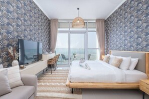 Quarto de hotel moderno com uma cama grande, televisão, escrivaninha e varanda com vista.