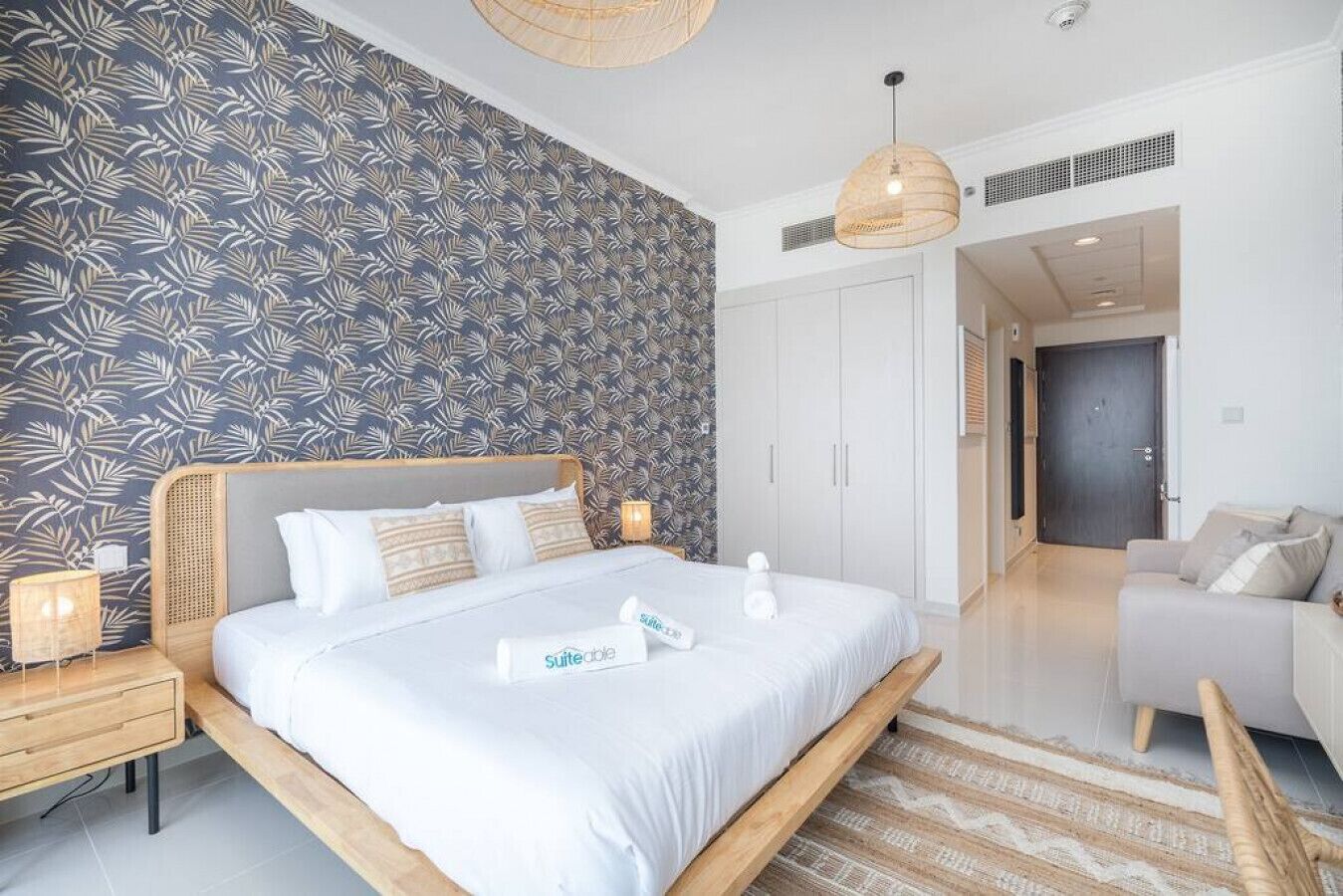 A modern bedroom with a large bed, a bedside table, a nightstand, a hanging light, and a wardrobe.