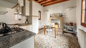 Cuina amb forlla de gas, armaris blancs, sostre de fusta i terra de rajola.