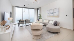 A modern living room with a sofa, a coffee table, and a dining area with a table and chairs. - Sunset spot with breathtaking view by Suiteable (Dubai)
