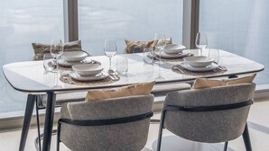 A dining table set for four with a view of the city through large windows. - Sunset spot with breathtaking view by Suiteable (Dubai)
