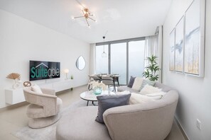 A modern living room with a sofa, a coffee table, a TV, and a dining area.