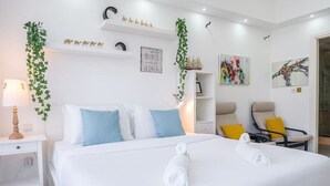 Hotellihuone, jossa on suuri sänky, kaksi yöpöytää, tuoli, työpöytä ja kirjahylly.