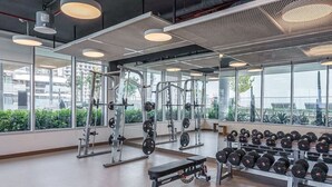 A gym with weightlifting equipment, benches, and dumbbells. - Your beachfront luxe escape experience - Suiteable (Dubai)