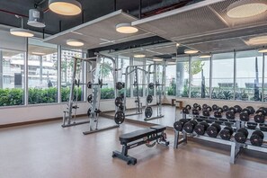 A gym with weightlifting equipment, benches, and dumbbells.