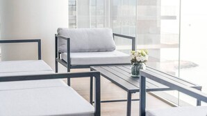 Ein modernes, minimalistisches Zimmer mit einem grauen Sofa, einem kleinen Tisch und einem Blumenstrauß.
