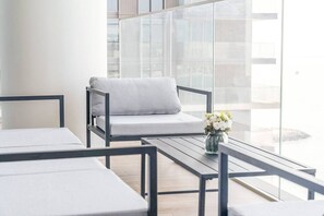 A modern, minimalist room with a grey sofa, a small table, and a vase of flowers.