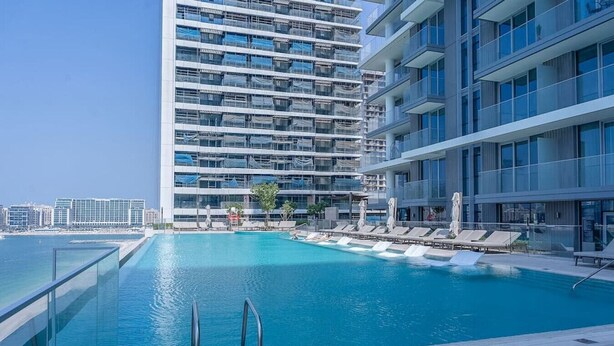 A modern hotel with a rooftop infinity pool, lounge chairs, and a clear view of the city skyline. - Your beachfront luxe escape experience - Suiteable (Dubai)