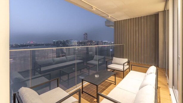 Ein Balkon mit Glastrennwand, einem weißen Sofa und einem kleinen Tisch.