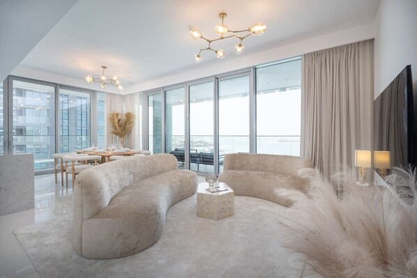 A modern living room with a sofa, a coffee table, and a dining area with a table and chairs.