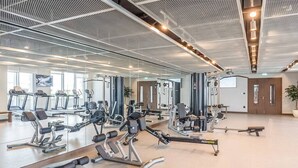 Ein Fitnessstudio mit unterschiedlichen Trainingsgeräten, großen Spiegeln und einer großzügigen Gestaltung.