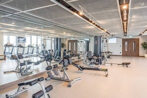A gym with various exercise equipment, large mirrors, and a spacious layout.