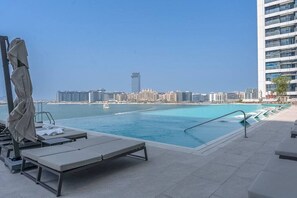A rooftop pool with lounge chairs and a view of the city skyline. - Your beachfront luxe escape experience - Suiteable (Dubai)