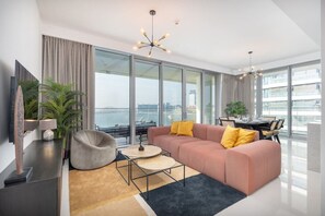 A modern living room with a sofa, a coffee table, a TV, and a view of the city.
