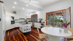 Una cocina moderna con armarios blancos, una isla de madera y un comedor con sillas de mimbre.