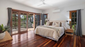 Un dormitorio espacioso con una cama grande, un ventilador de techo y un ventanal corredero que da a un área exterior.