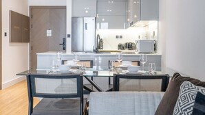 Une cuisine moderne avec un coin repas, comprenant une table dressée pour quatre personnes, ainsi que des chaises.