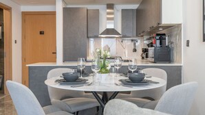 A modern dining area with a round table set for four, surrounded by grey upholstered chairs. - Modern Comfort in a Spacious Apartment - Suiteable (دبي)