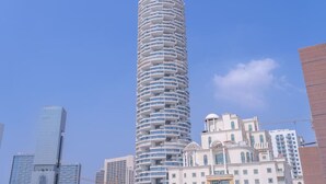 A tall, cylindrical hotel with multiple balconies, surrounded by other buildings. - Modern Comfort in a Spacious Apartment - Suiteable (دبي)