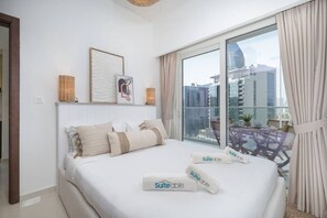 Ein Hotelzimmer mit einem großen Bett, Blick auf die Stadt durch das Fenster und einem Balkon mit Tisch und Stühlen.