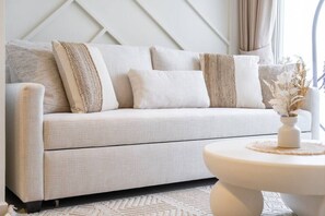 Ein modernes Wohnzimmer mit einem hellen Sofa, einem runden Couchtisch und einer dekorativen Vase.