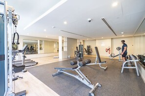 Ein Fitnessstudio mit Cardiogeräten, Kraftstationen und einer Spiegelwand.