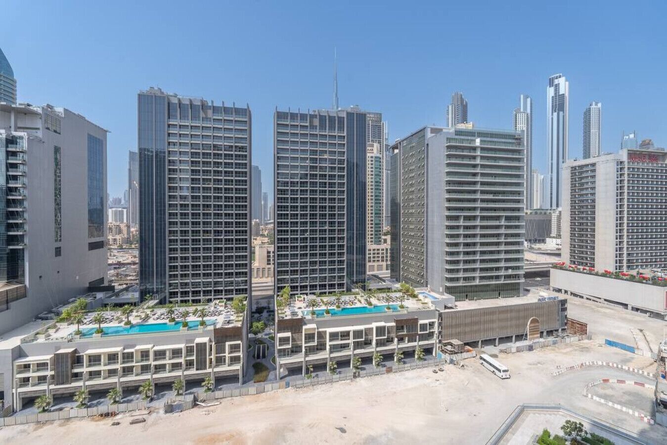 Un complexe hôtelier moderne comprenant plusieurs immeubles de grande hauteur, une piscine et un parking.
