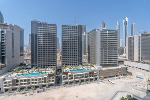 A modern hotel complex with multiple high-rise buildings, a swimming pool, and a parking area.