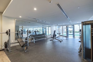 Et moderne fitnesscenter med forskellig træningsudstyr, store vinduer og en lys, rummelig indretning.